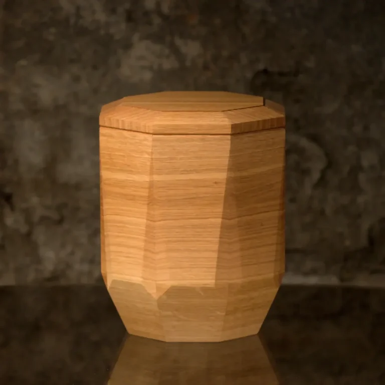 Eichenholzurne E2 handgefertigtes Unikat Holzurne mit sechseckigem Körper und Facettenschliff an den Längskanten, glatter Oberfläche. Die Urne verjüngt sich im unteren Bereich.